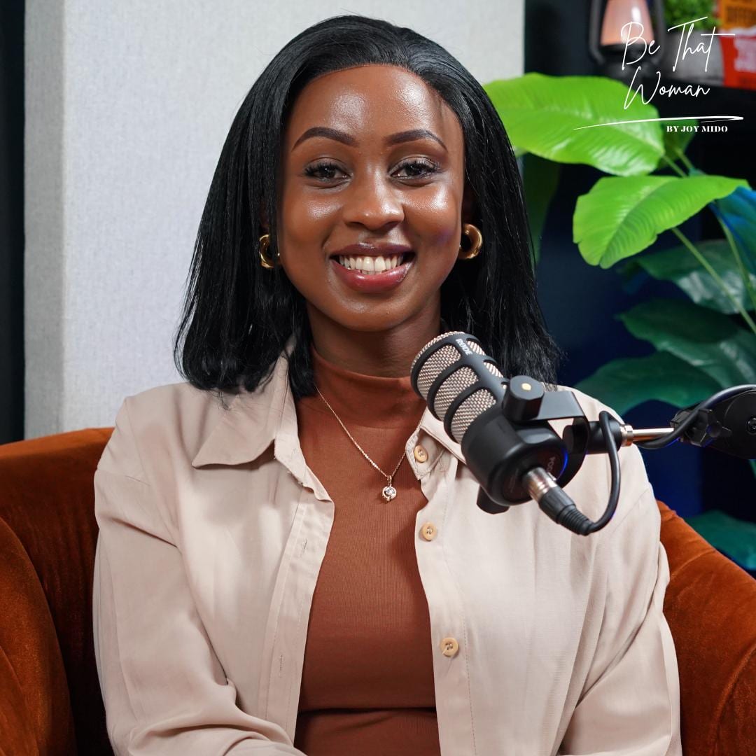 Joy Mido smiling at the Be That Woman podcast microphone